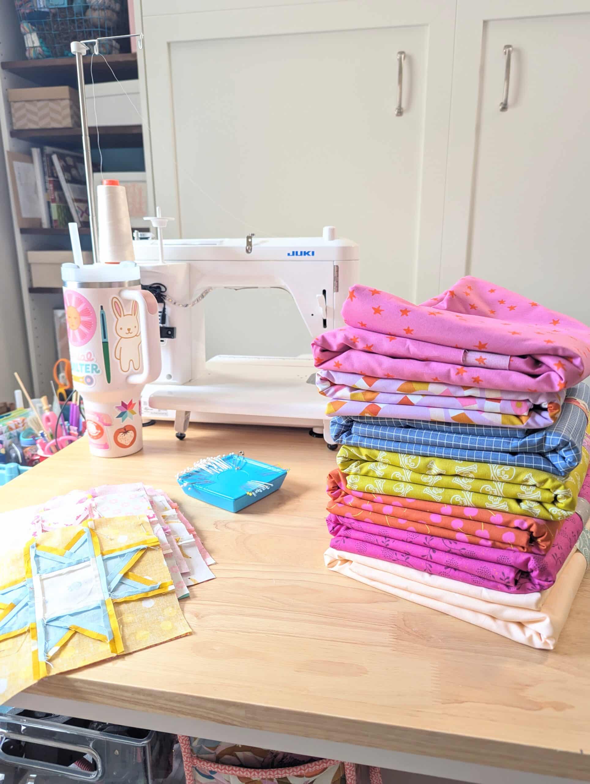 A stack of large cuts of fabric sit on a wooden table.