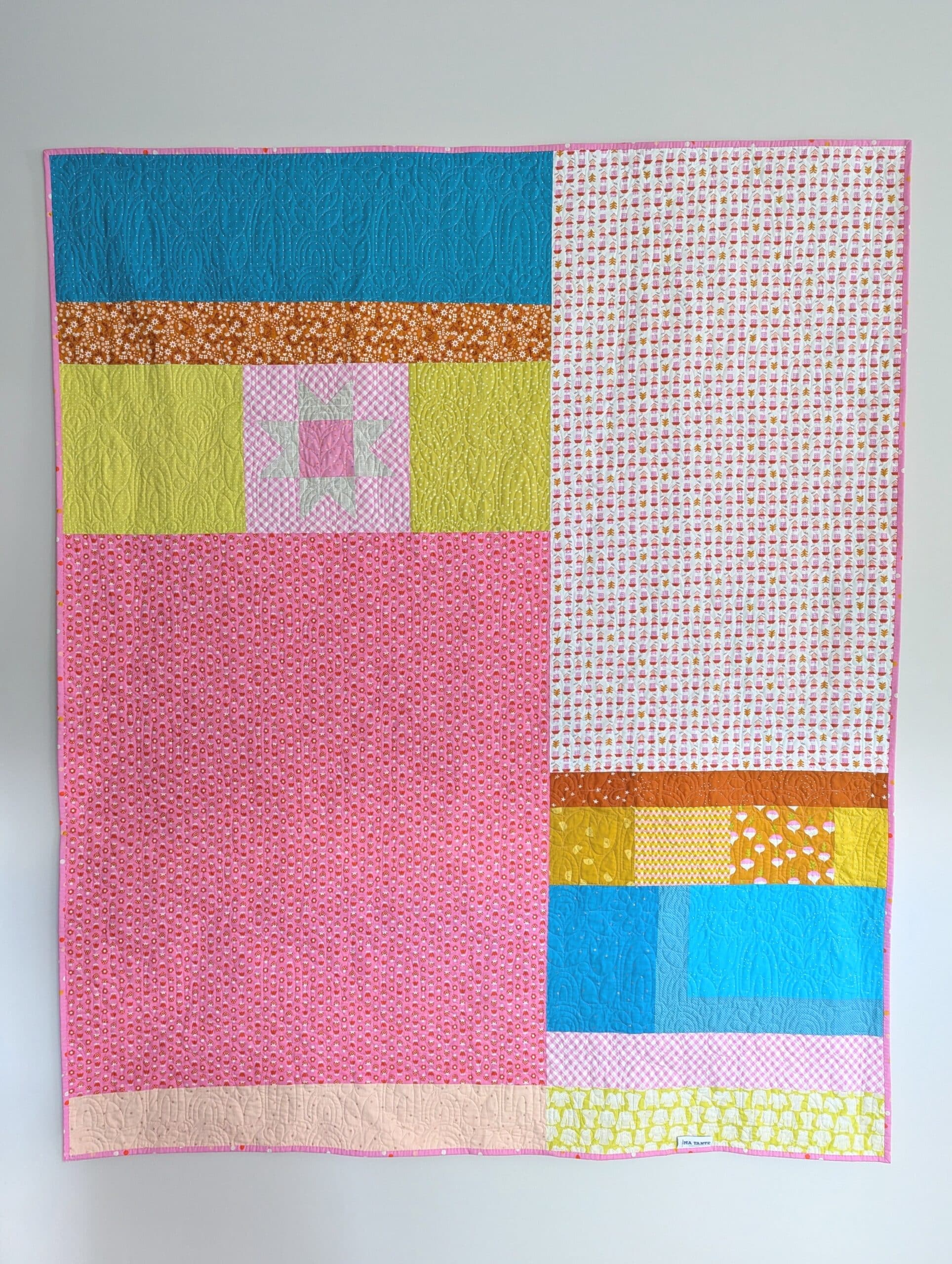 Quilt hangs on wall, showing the pieced backing.