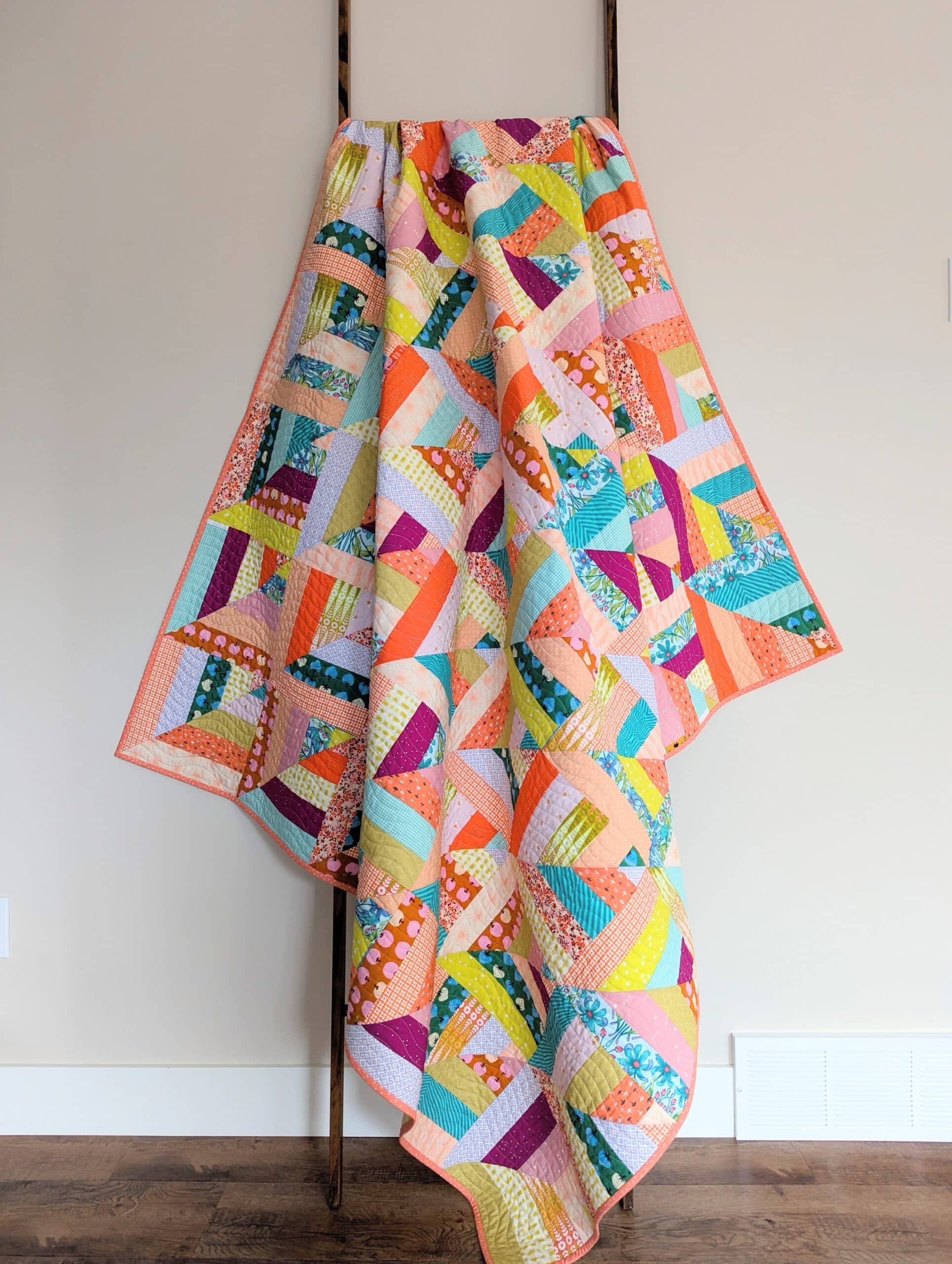 The finished quilt is draped over a wooden ladder.