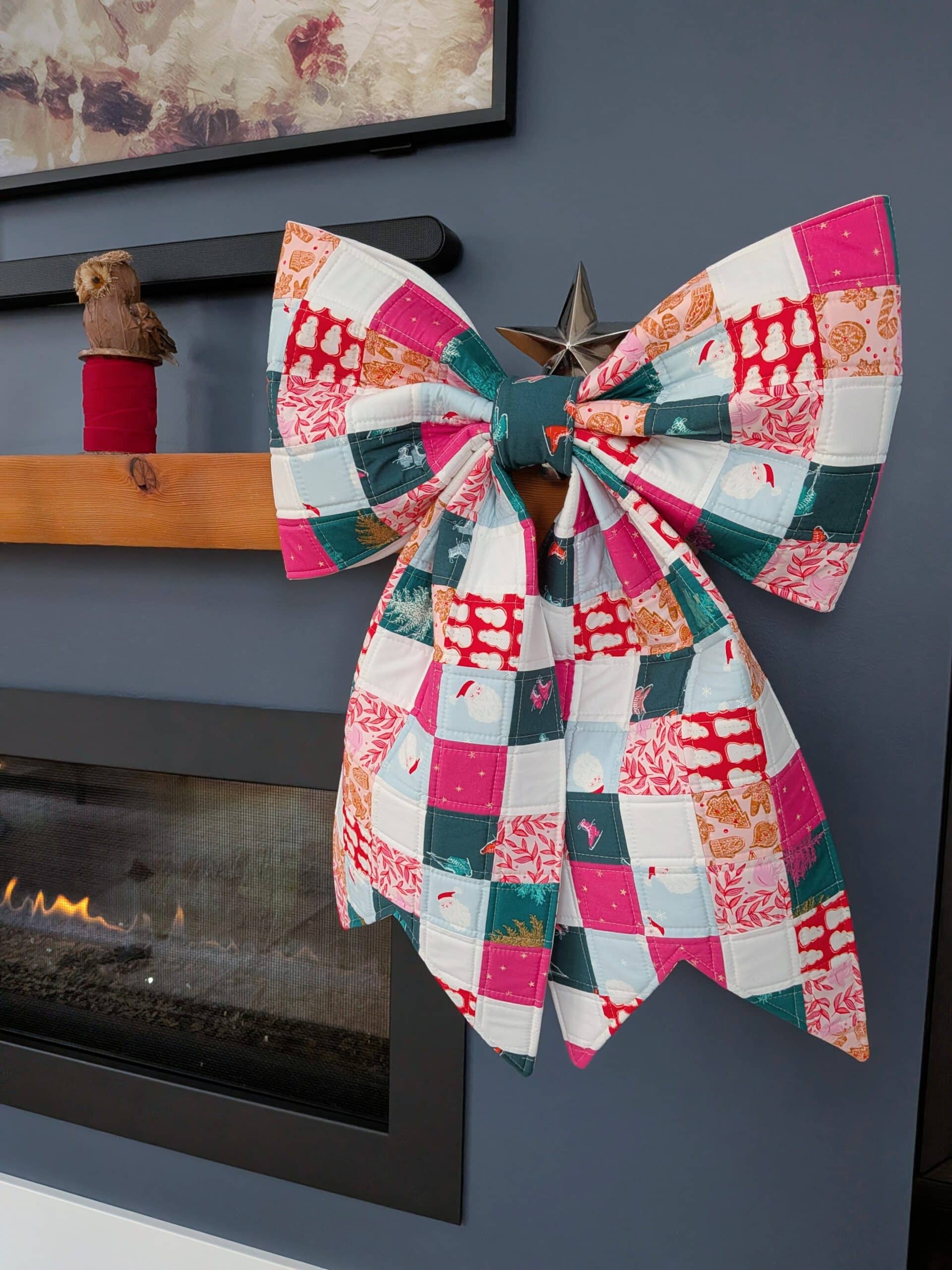 A patchwork bow hangs on the mantel of a fireplace.