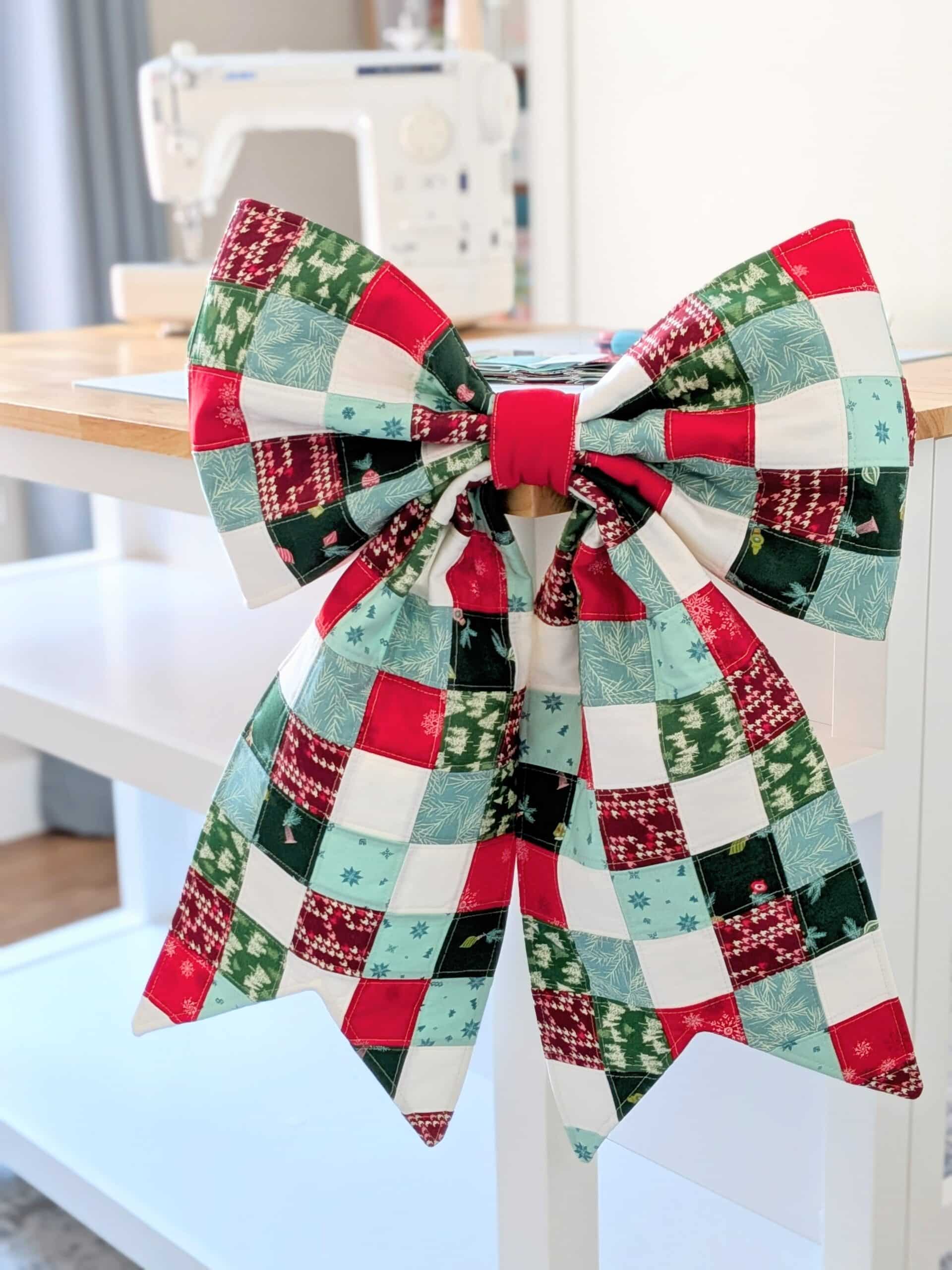 A quilted bow hangs on the corner of a worktable in a sewing room.