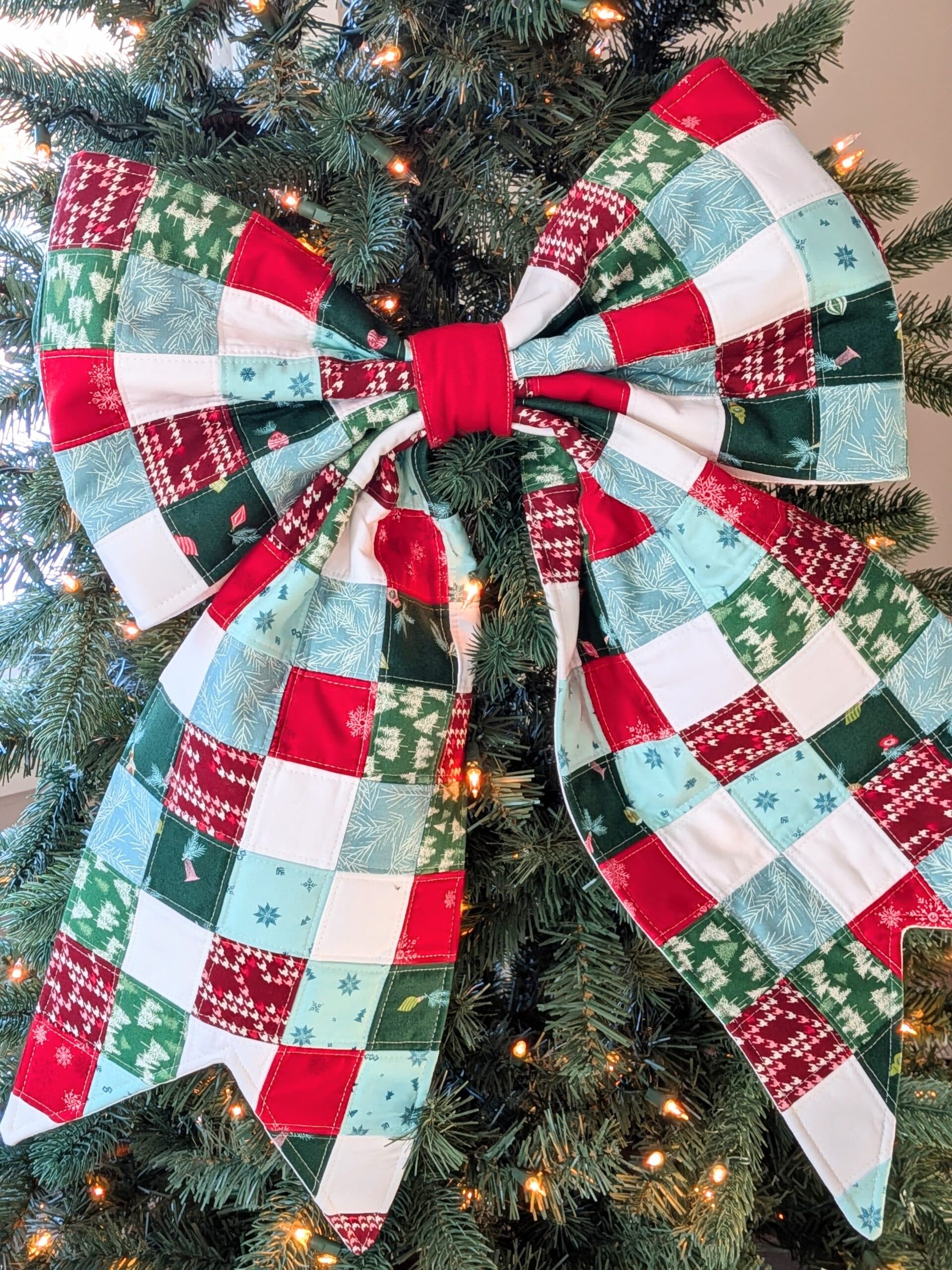 A quilted bow hangs on a Christmas tree