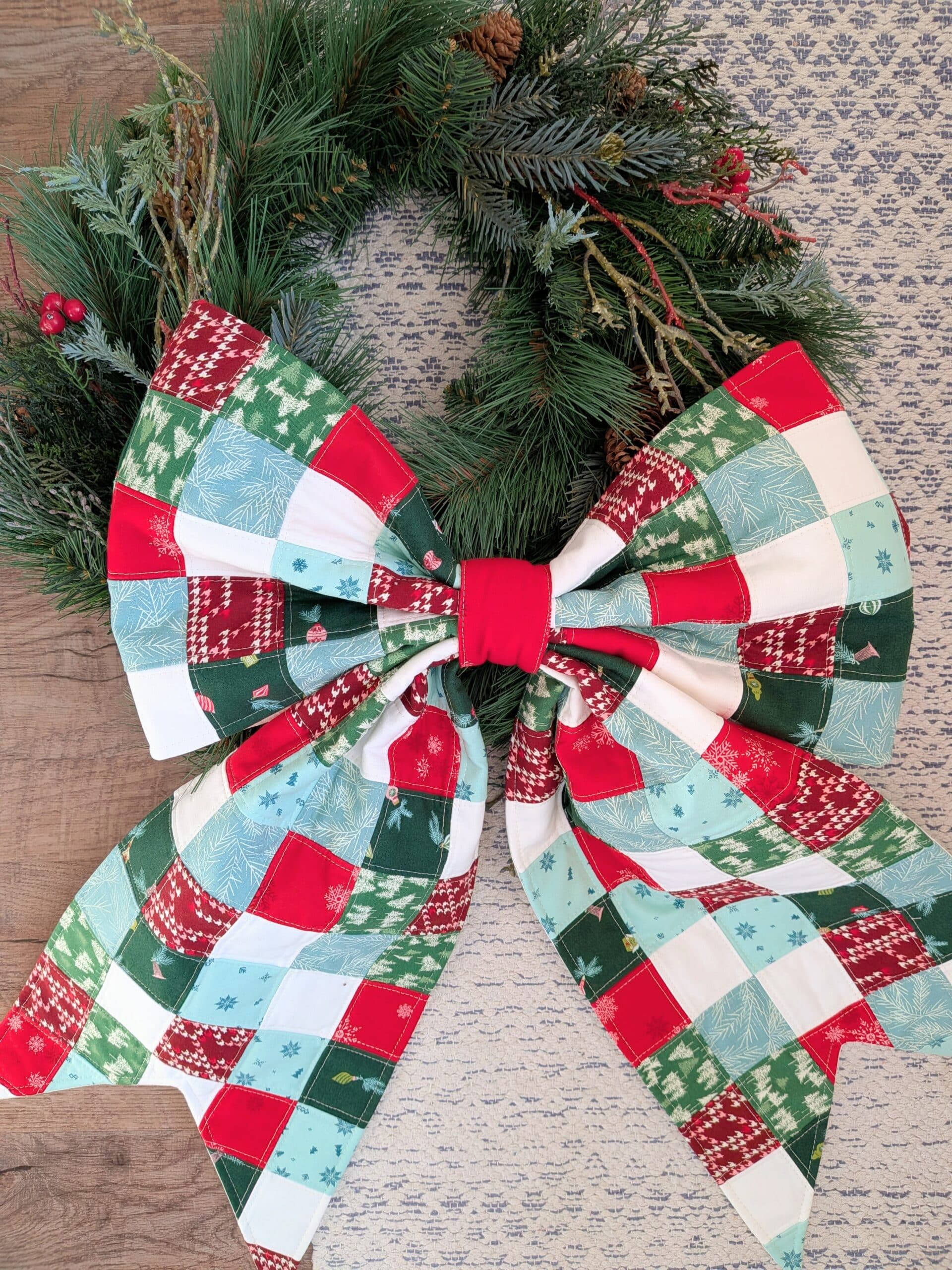 A quilted bow lies next to a wreath