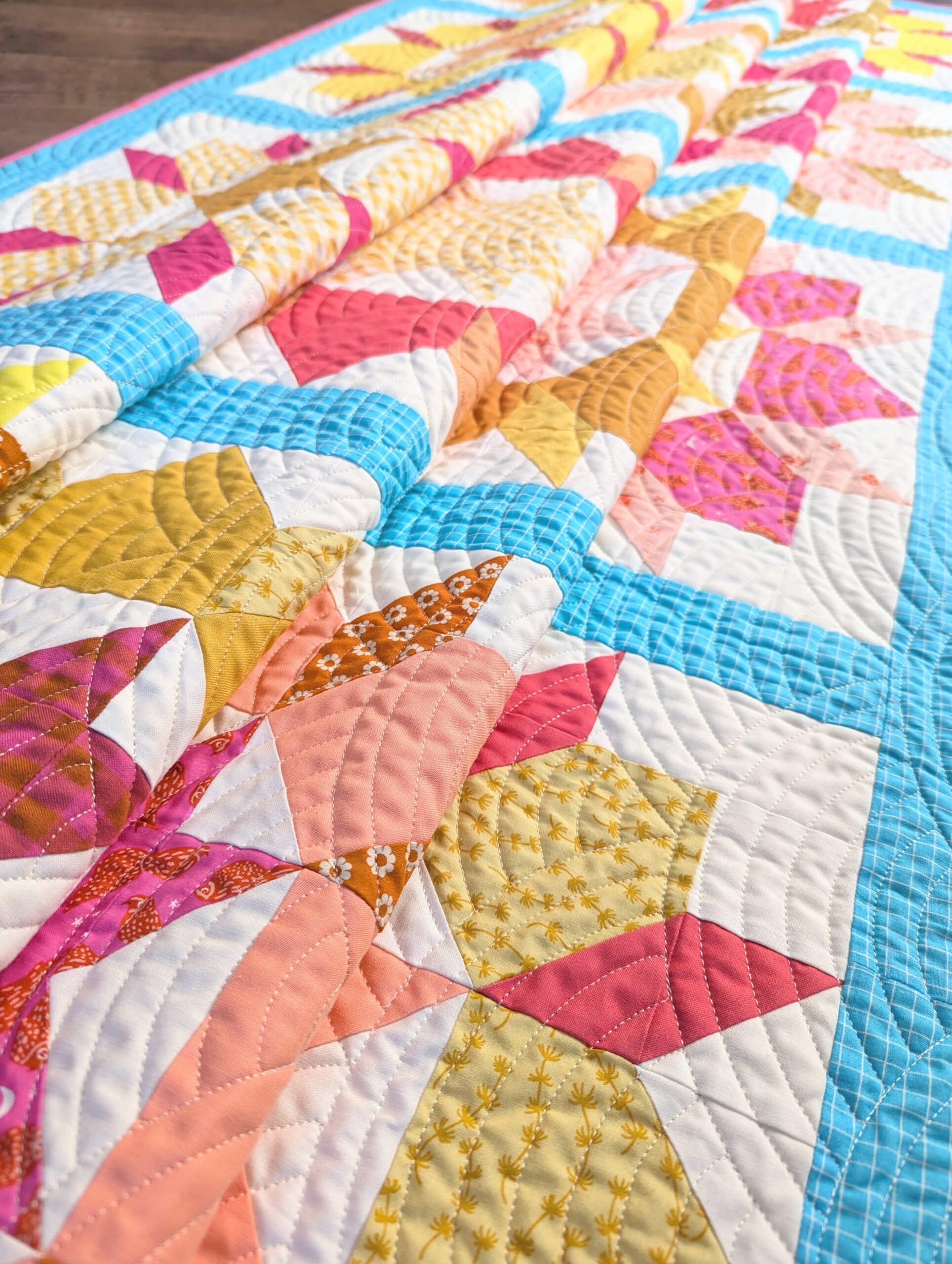 A bright and colourful quilt is folded multiple times and is seen from a low angle.