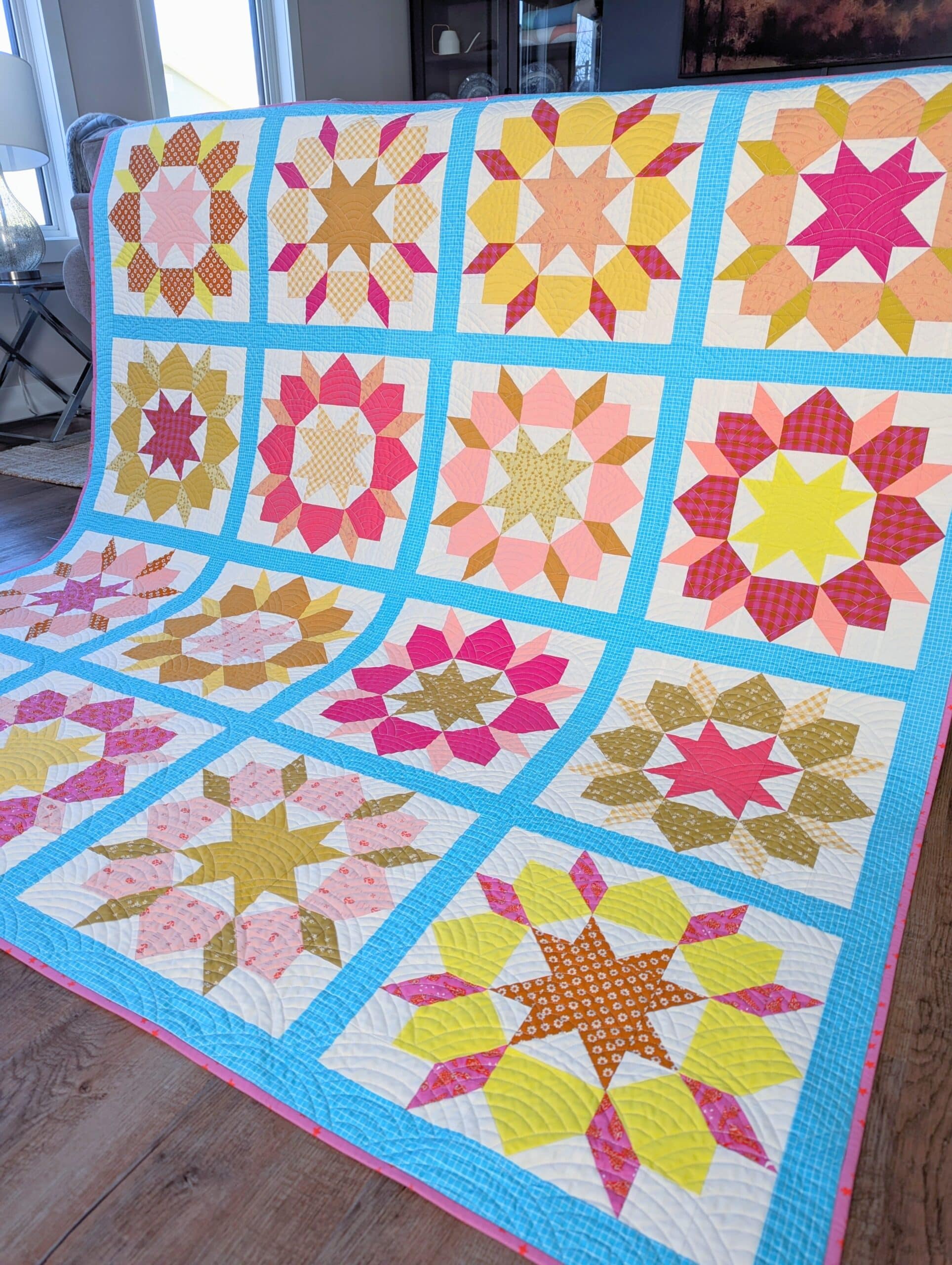 The bright and colourful quilt is draped over the back of a sofa.