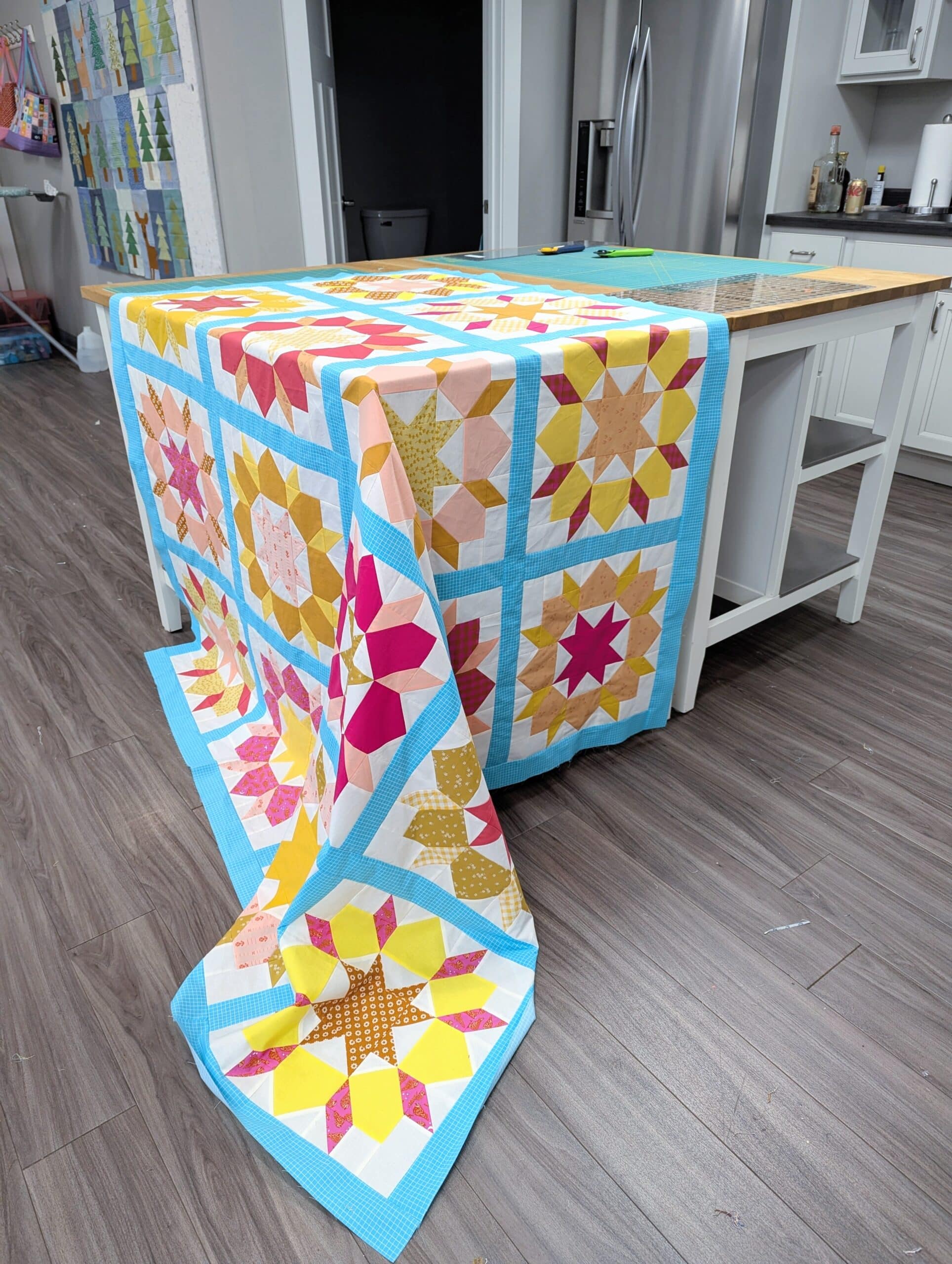 The quilt top is draped over a cutting table at a retreat center.