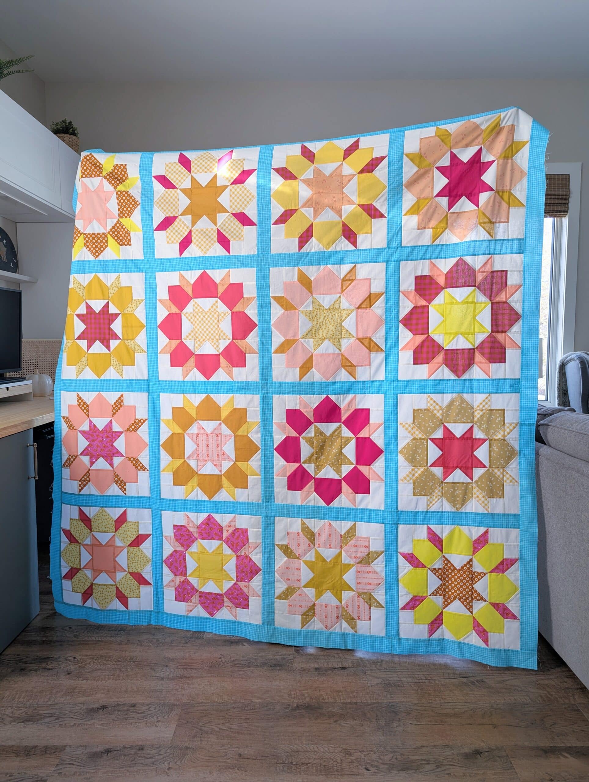 Shelly holds up the completed quilt top.