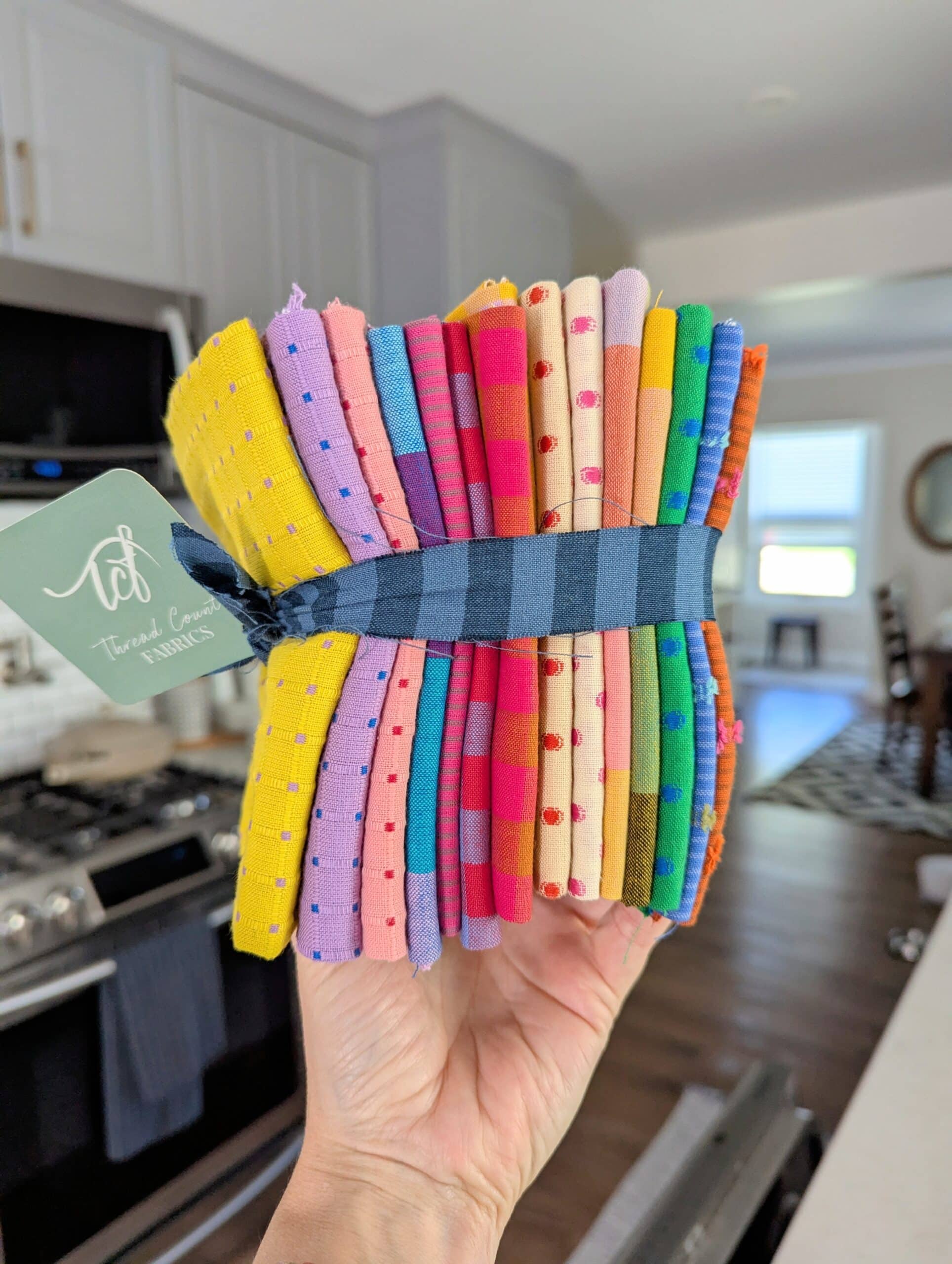 Shelly holds a stack of colourful woven fat quarters.