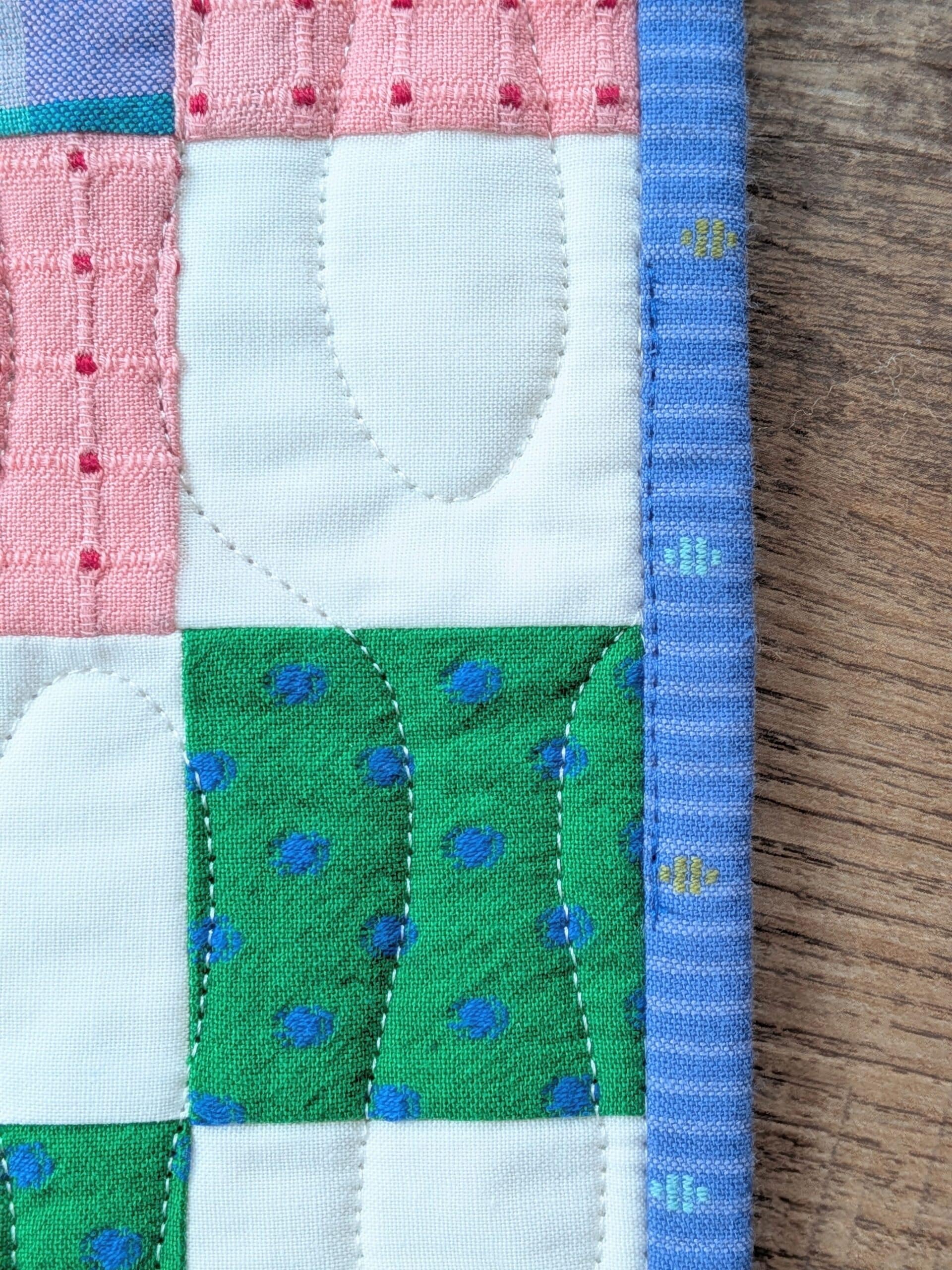 A closeup view showing a small section of stitching on top of the blue binding.