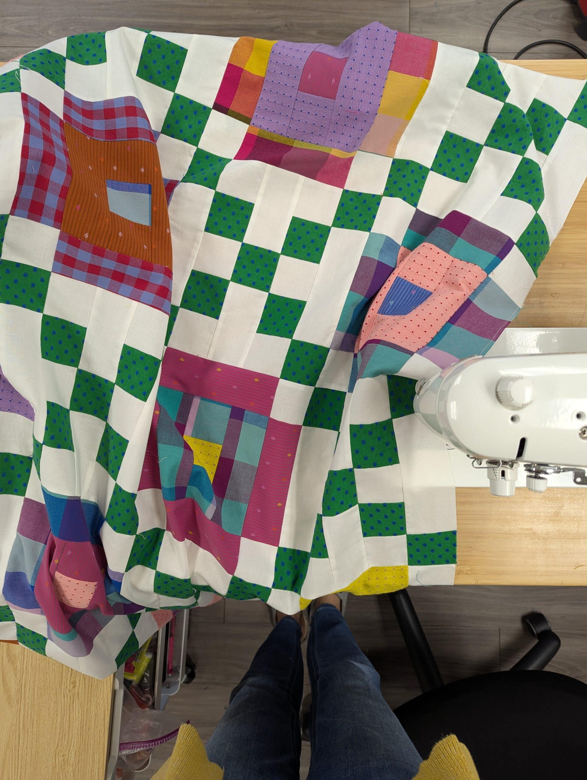 An overhead view of the finished quilt top at a sewing table.