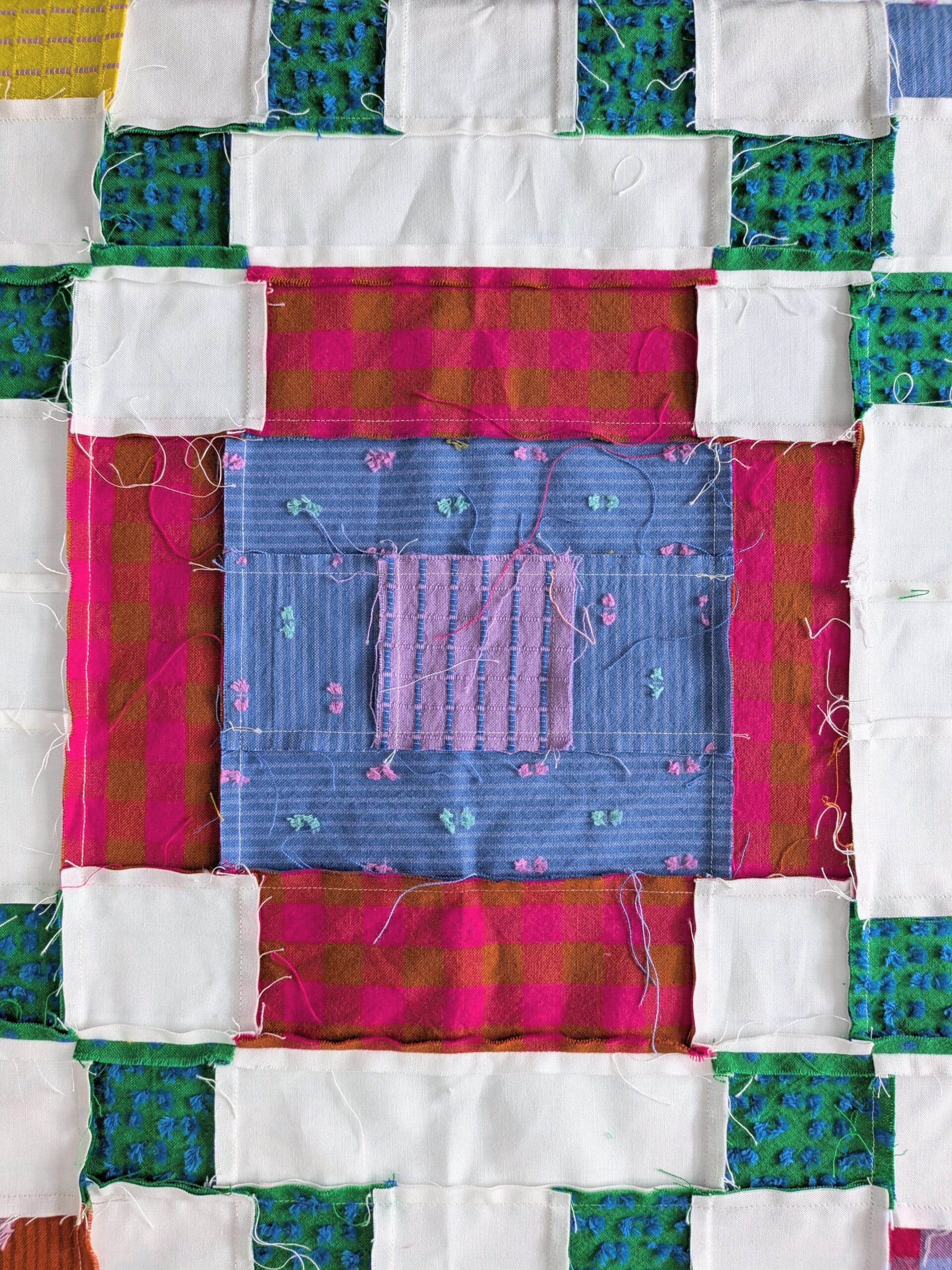 The back of a quilt block shows many many loose threads.