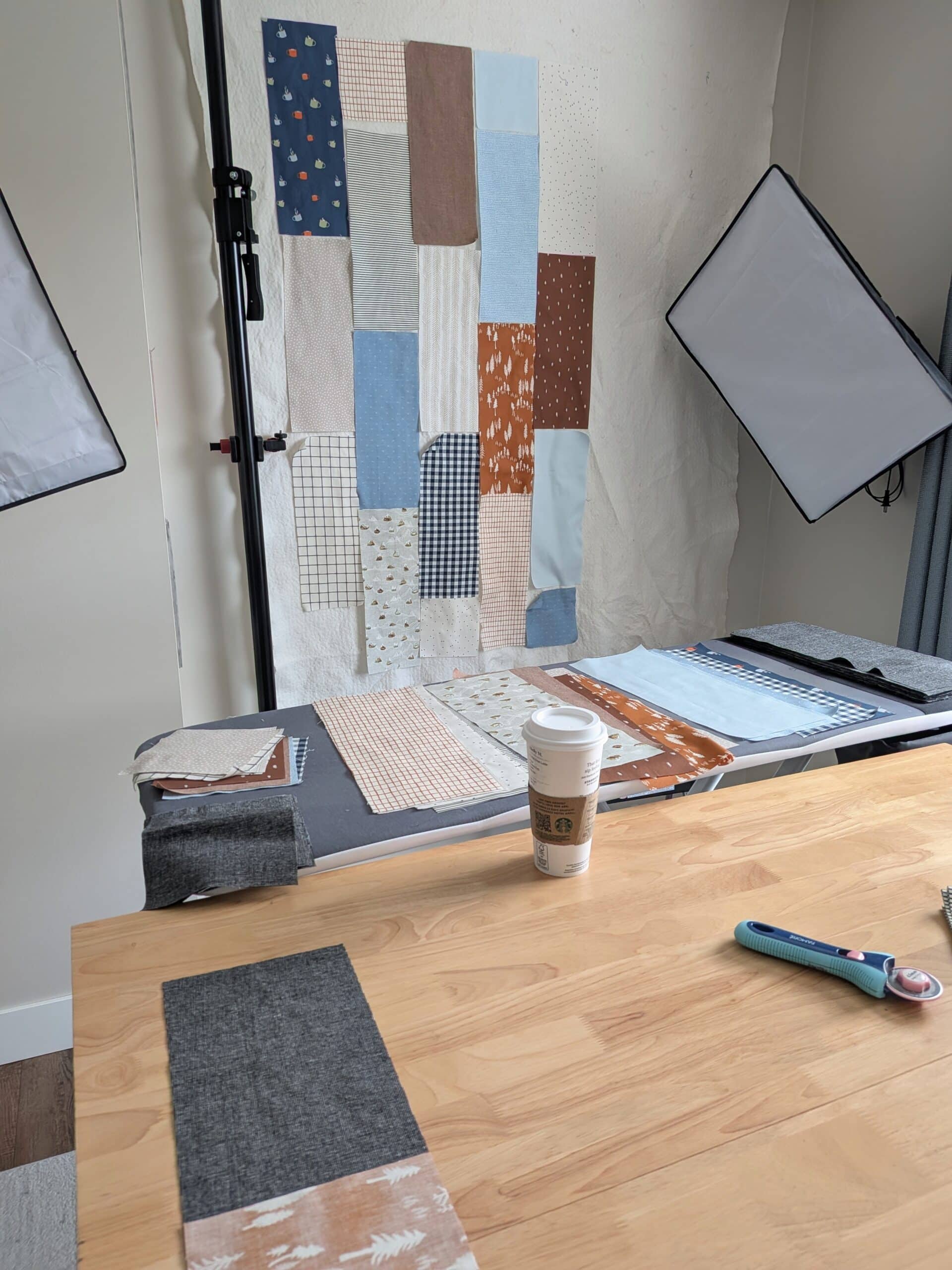 Several large rectangles of blue, brown, and light coloured fabric are placed on a design wall.