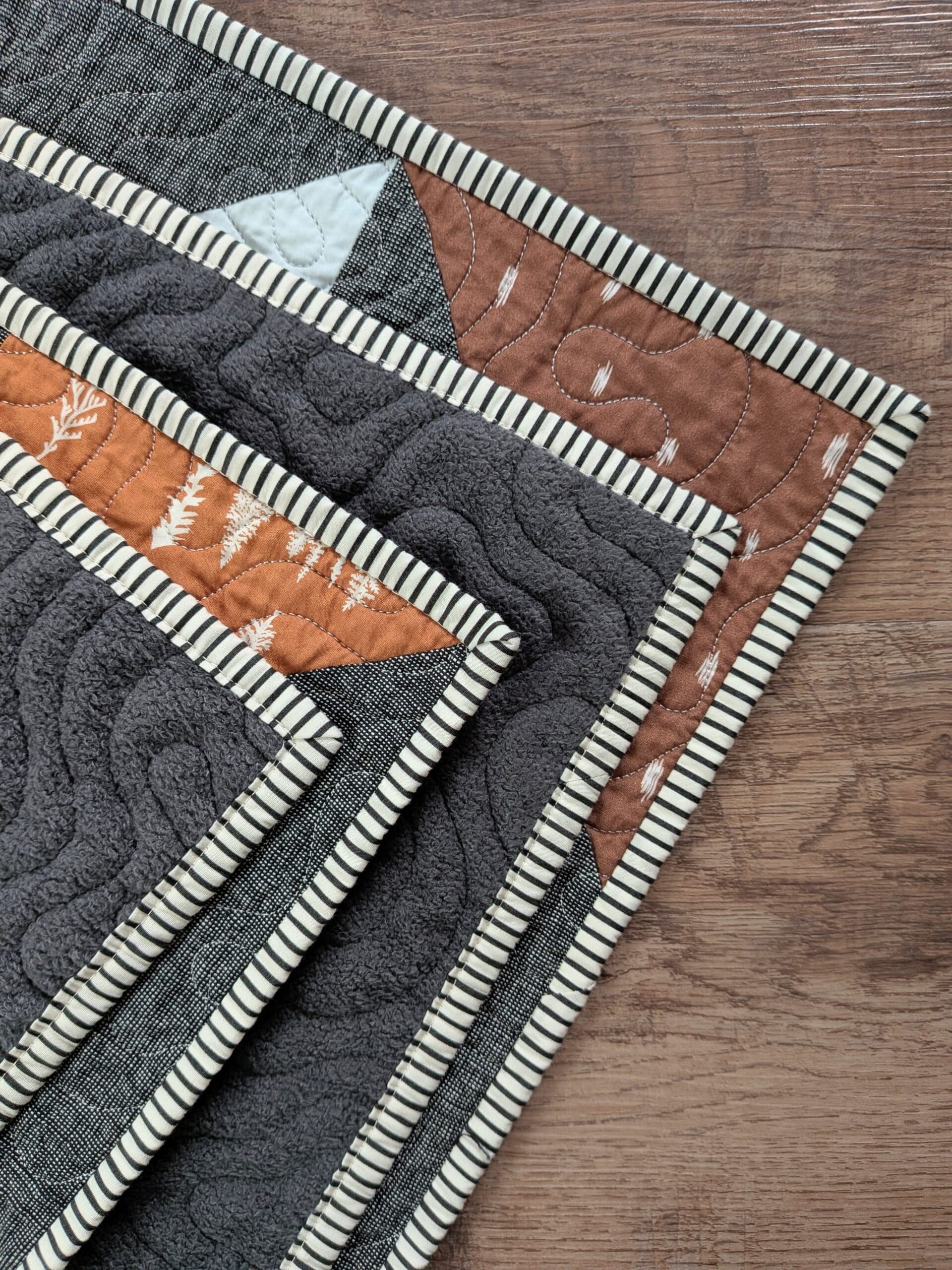 All four corners of a quilt's striped binding are seen at once.