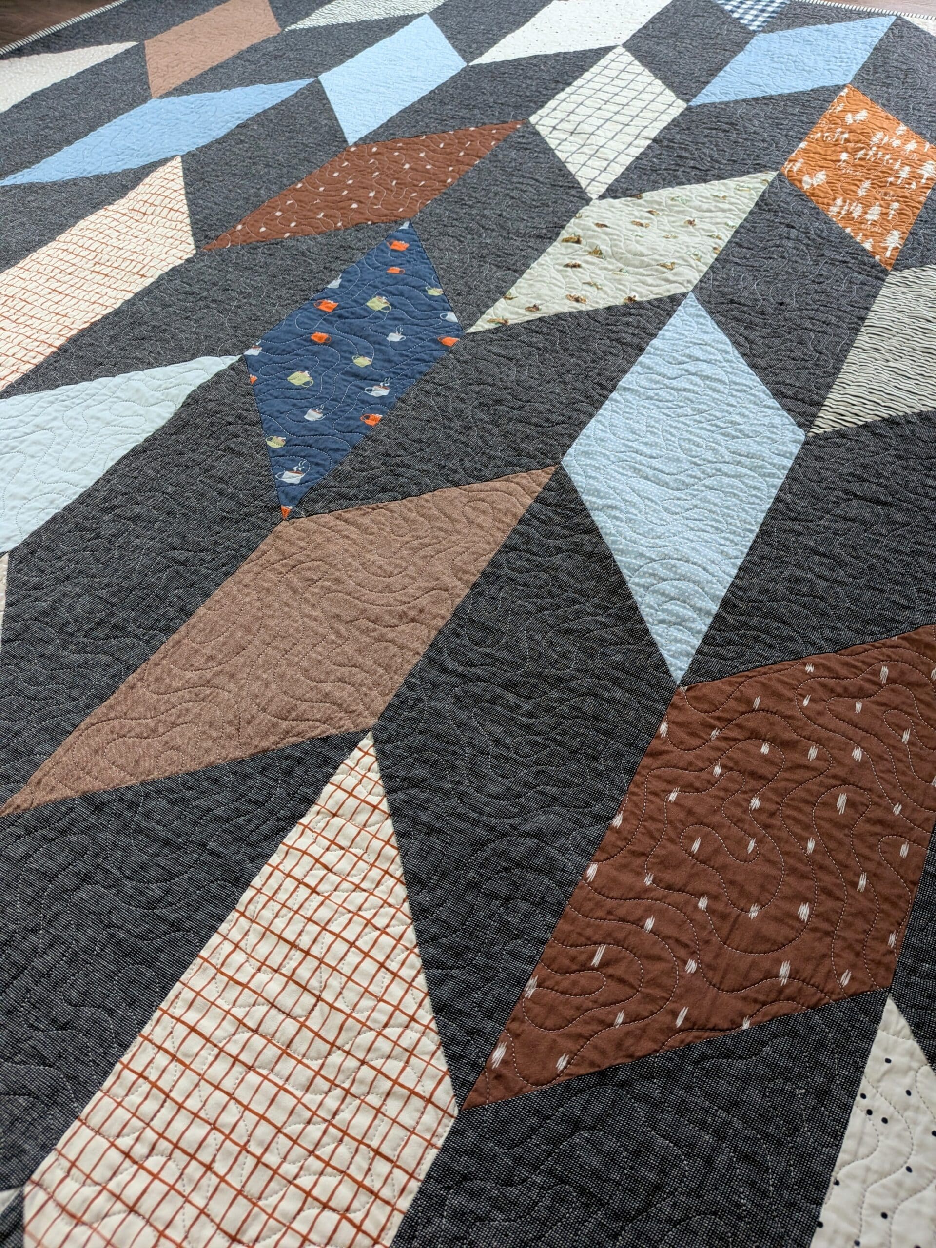 A chevron quilt is laid on the ground and viewed from a low angle.
