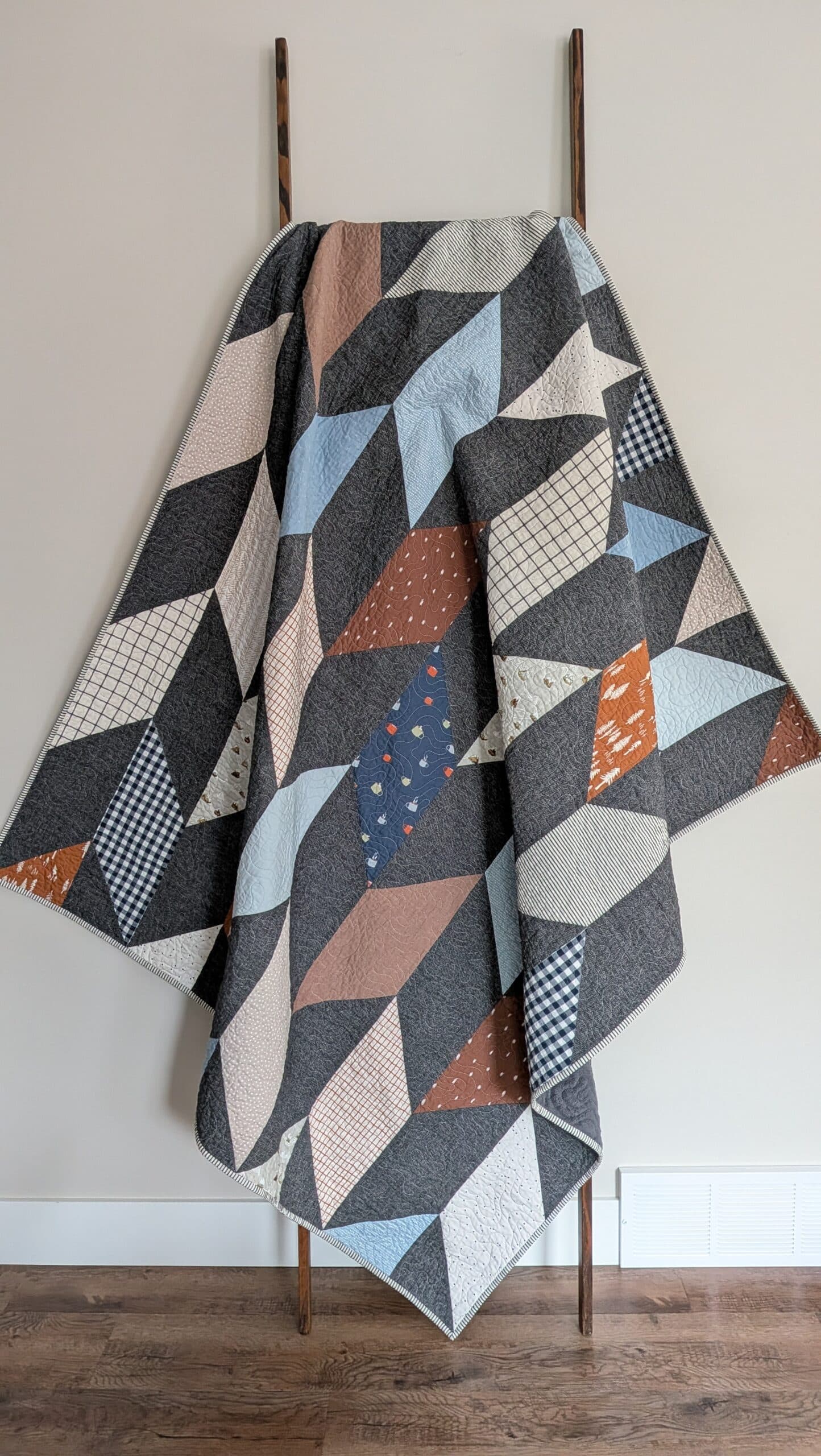 A chevron quilt hangs over a wooden ladder.