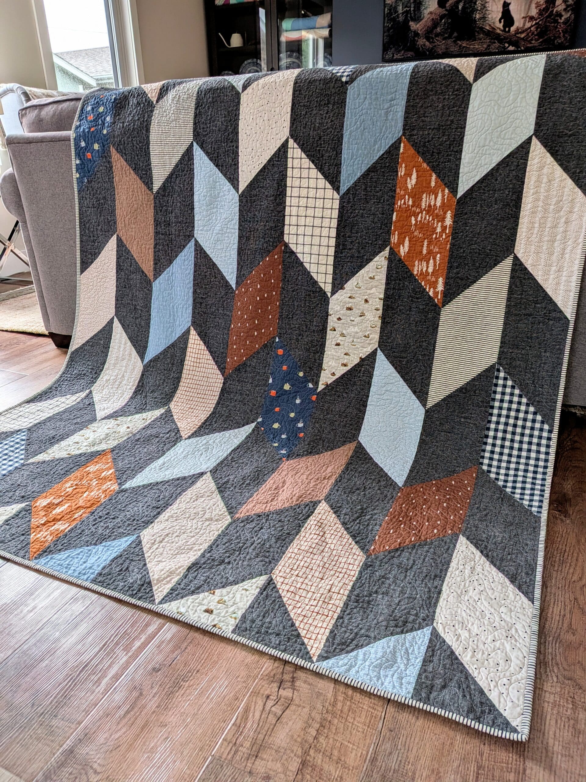 A chevron quilt is draped over the back of a sofa.