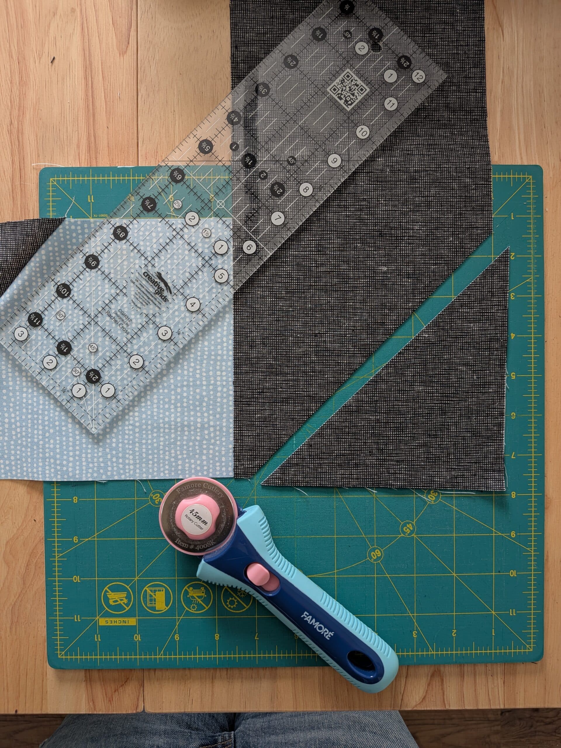 Two pieces of fabric are laid on top of each other at a right angle, and one corner has been cut off using a rotary cutter.